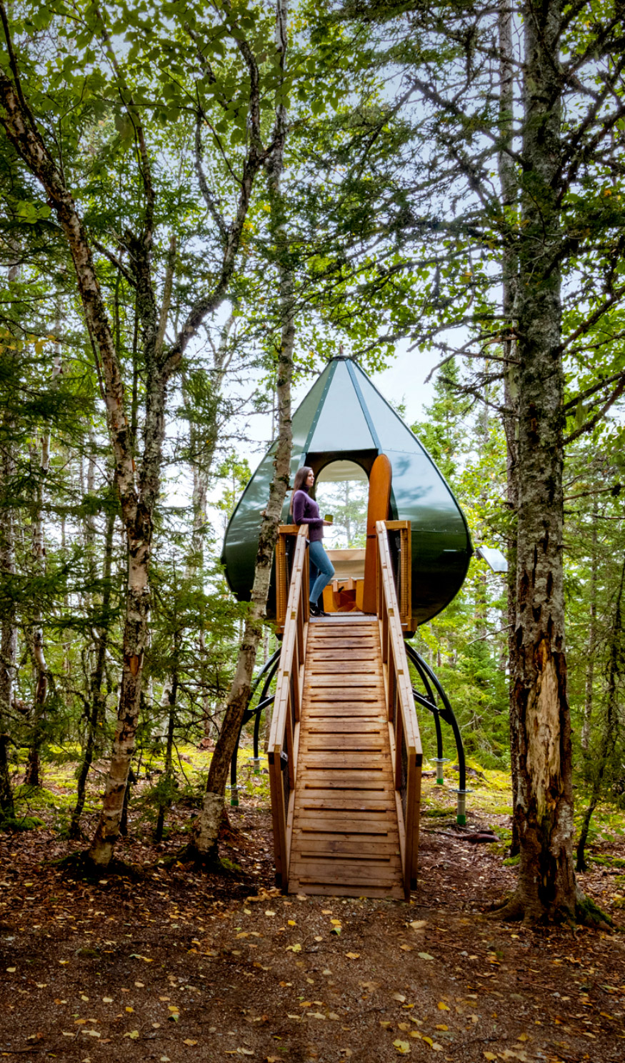 Woman standing outside an Oasis Pod, a modern structure for camping in Terra Nova National Park