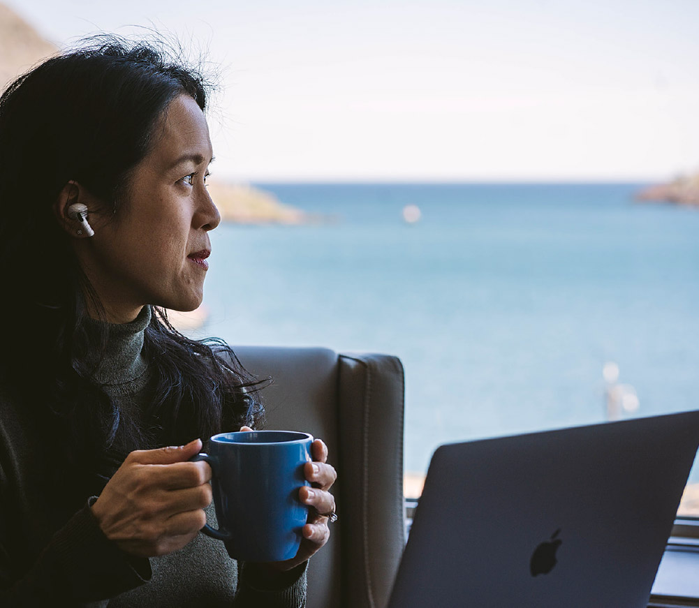 A woman drinking coffee while working on a laptop