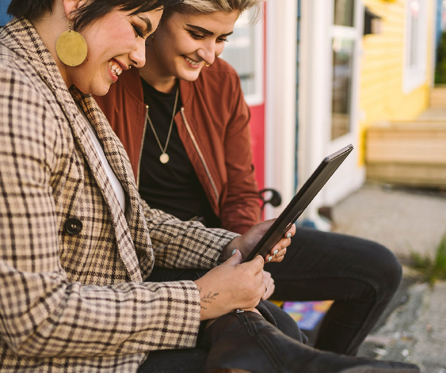 Two people smiling at a tablet