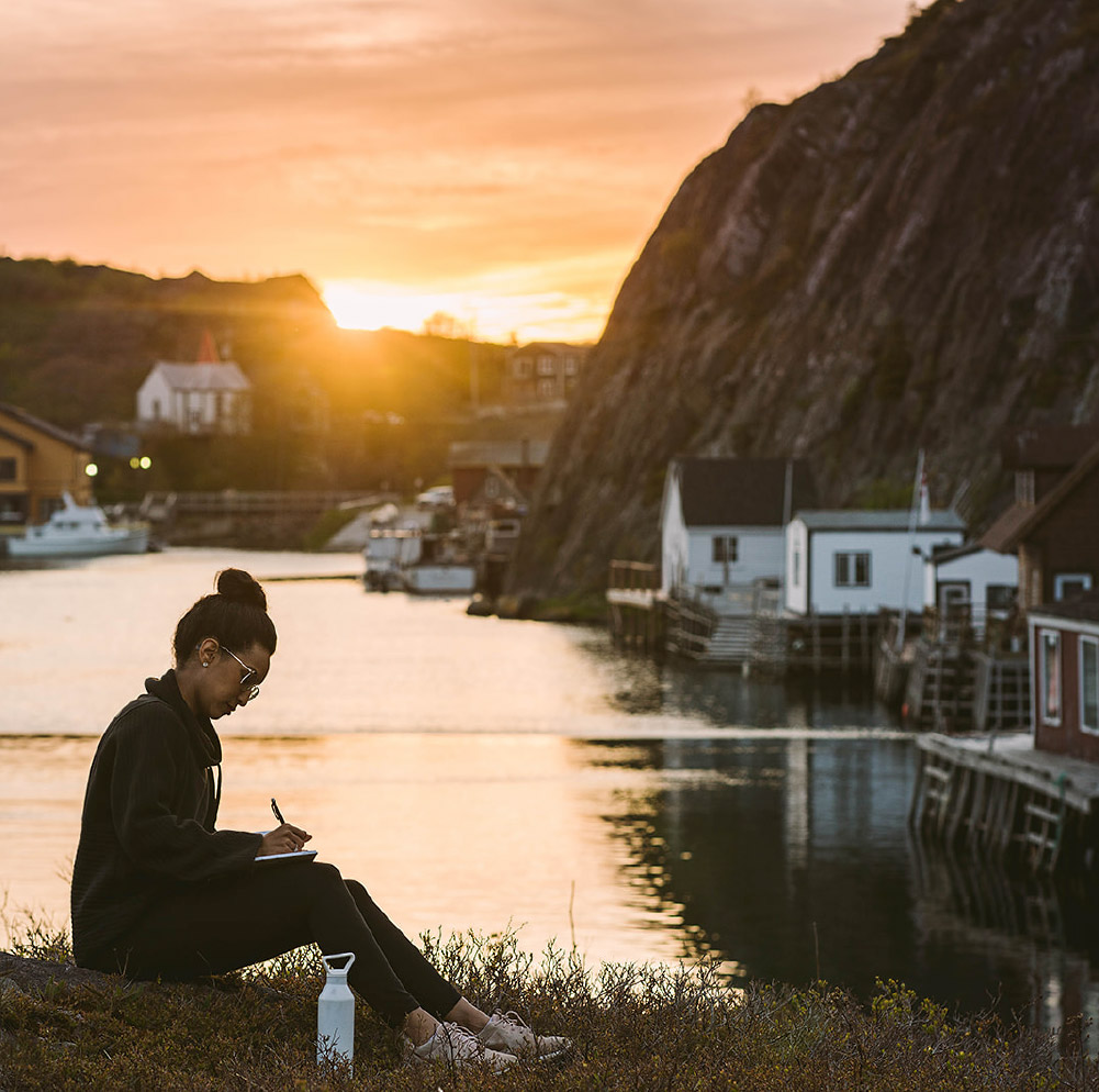 A woman studying outdoors by the water in Quidi Vidi, St. John’s
