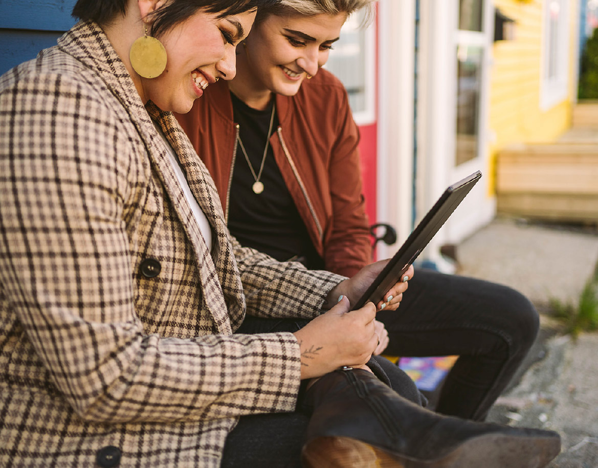 Two people smiling at a tablet