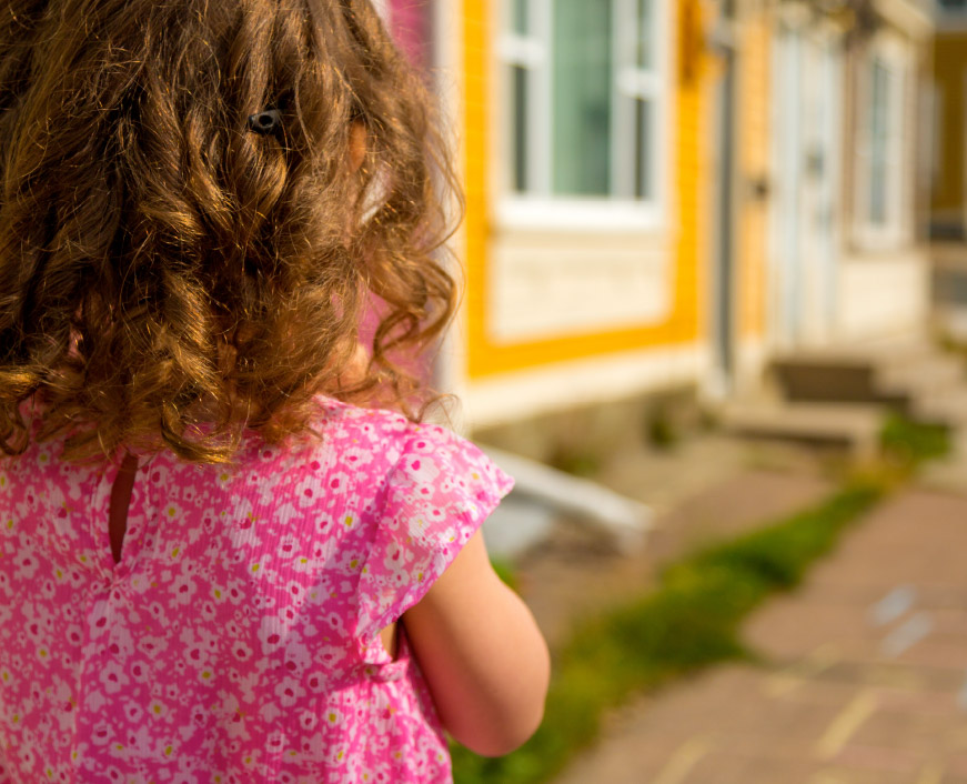 Young girl walking by colourful homes in Jellybean Row, downtown St. John’s