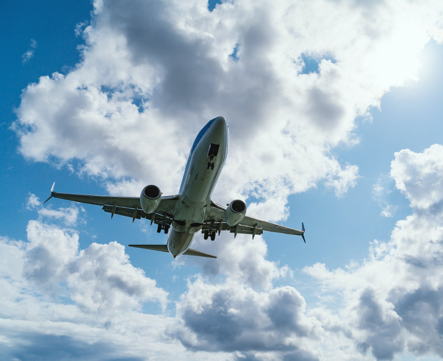 Plane flying through the sky against a backdrop of clouds