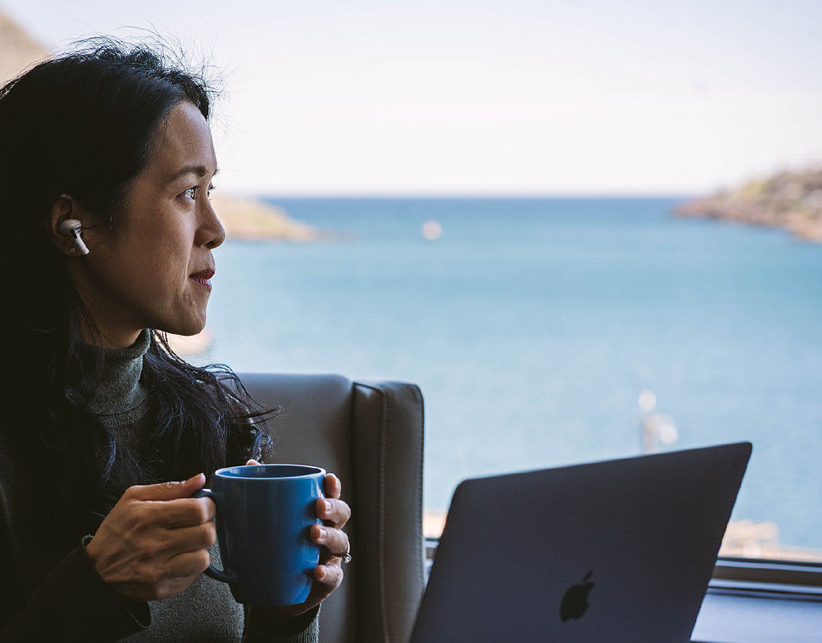 A woman drinking coffee while working on a laptop